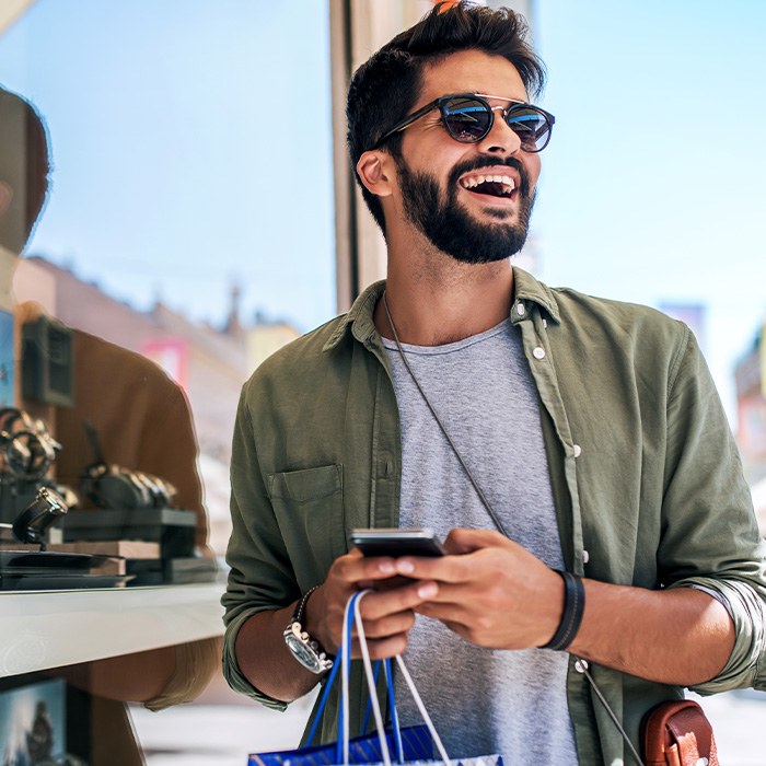 Man with sunglasses smiling while shopping outside