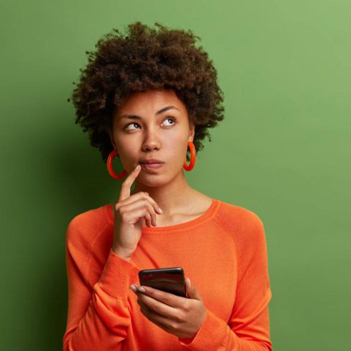 Woman holding her phone and looking confused