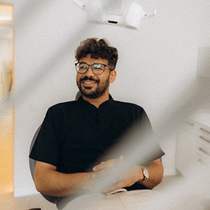 Patient with black glasses smiling in treatment chair