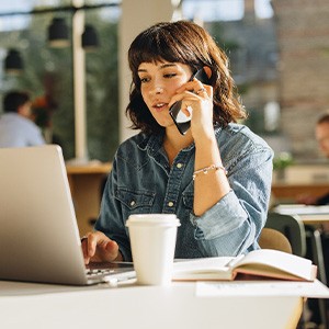 Woman talking on the phone while working on a laptop