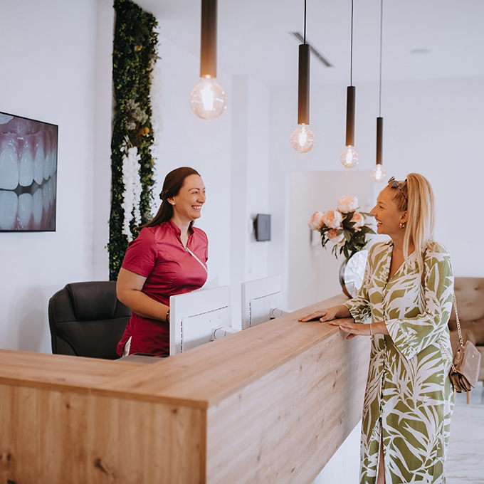Dental receptionist and patient smiling together in lobby