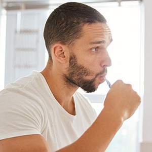 Man brushing his teeth in bathroom