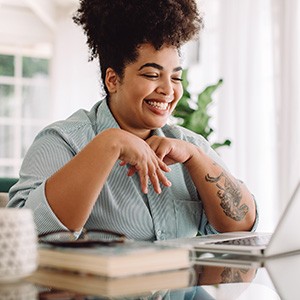 Woman smiling while working on a laptop at home
