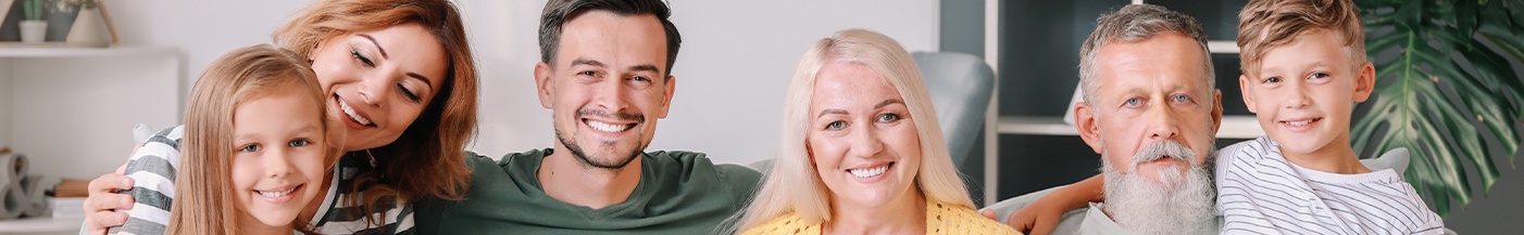 Family smiling at home after seeing a dentist near Wrightsville Beach