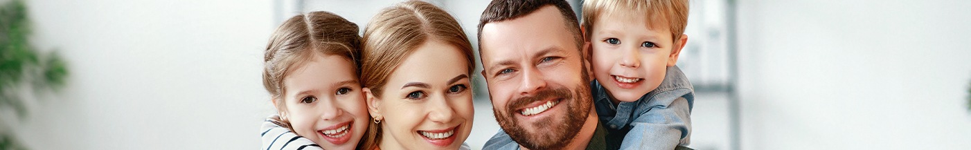 Family of four smiling after seeing a dentist near Mayfaire