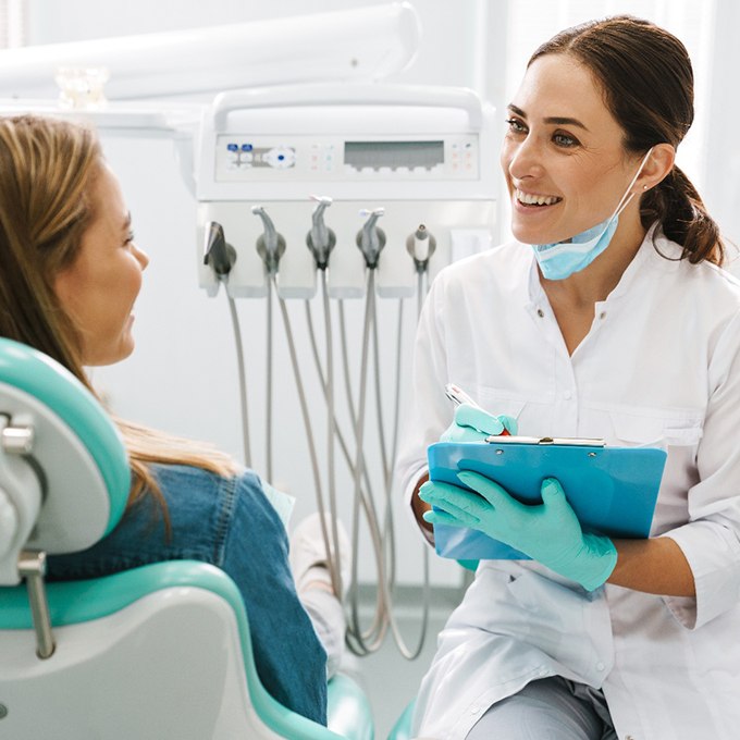 Smiling dentist taking notes on clipboard