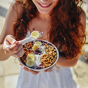 Woman smiling while eating acai bowl outside